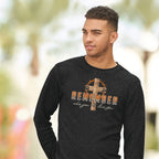 Man wearing a gray ong-sleeve shirt with a cross and text design outdoors.
